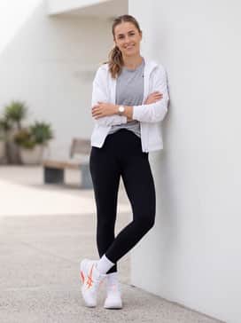 A sleek gym-to-street outfit consisting of high-waisted black leggings, a fitted grey marl technical tee, and a lightweight white windbreaker jacket.