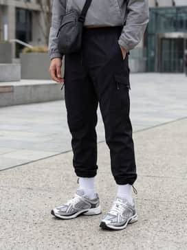 Skyjet Prisco Sneakers – Black technical cargo pants tucked into white crew socks, paired with a cropped windbreaker and a crossbody bag for a sleek, utility-focused look.