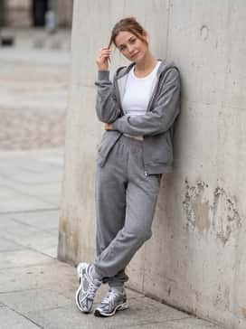 Grey marl oversized joggers and a matching zip-up hoodie over a white tank top for a coordinated, high-fashion athleisure ensemble.