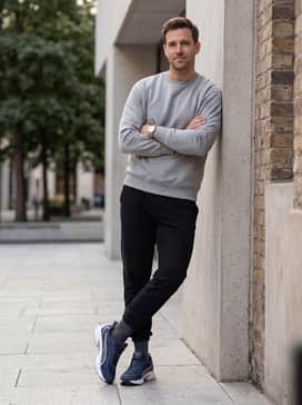 An athleisure-inspired ensemble with black tapered joggers, a fitted heather grey hoodie, and a silver-toned watch that complements the shoe's accents.