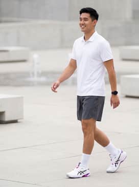 A professional on-court look featuring a crisp white moisture-wicking polo, charcoal grey technical shorts, and high-cut white athletic socks to emphasize the shoe's sleek profile.