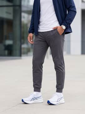 A sleek athleisure outfit with tapered charcoal joggers, a fitted white crew-neck t-shirt, and a lightweight navy windbreaker to highlight the shoe's blue accents.
