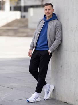 A modern streetwear look pairing slim-fit black denim with a cuffed hem, a cobalt blue oversized hoodie, and a silver-grey bomber jacket.