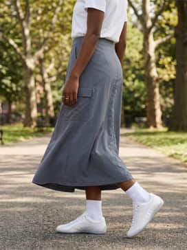 Speedcat Anodized Womens Sneakers – A technical nylon midi skirt in a slate grey, a tucked-in vintage graphic t-shirt, and oversized wrap-around sunglasses for a futuristic streetwear look.