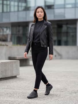 High-waisted black skinny jeans, a tucked-in charcoal mock-neck sweater, and a black leather biker jacket for a sharp, monochromatic street look.
