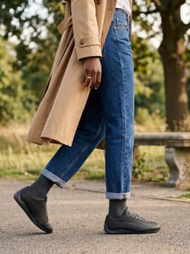 Speedcat Anodized Womens Sneakers – Straight-leg indigo denim with a French-tucked white button-down shirt and a camel trench coat for a sophisticated, low-key professional look.