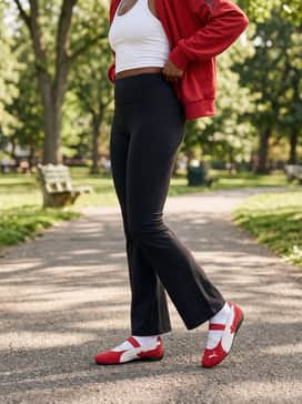 High-waisted black flared yoga pants and a white cropped racerback tank top, layered with a vintage-style red track jacket for a coordinated sporty look.