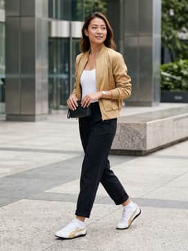 Slim-fit black joggers paired with a fitted white bodysuit and a gold-toned bomber jacket to echo the shoe's metallic accents.