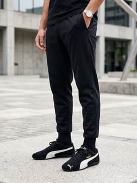 Tapered black joggers, a gold-accented graphic hoodie, and a minimalist baseball cap to complement the shoe's metallic detailing.