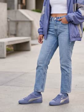 High-waisted light wash straight-leg jeans with a cropped white baby tee and a vintage-inspired nylon windbreaker in shades of blue and silver.
