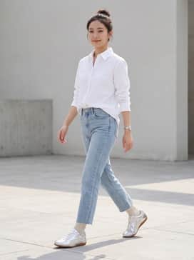 Light-wash straight-leg jeans with a raw hem, paired with an oversized white button-down shirt and minimalist silver accessories for a polished daytime look.
