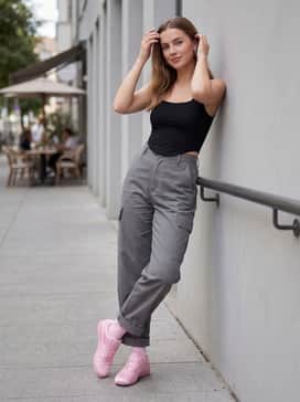 An edgy streetwear outfit consisting of oversized grey cargo trousers, a black fitted corset top, and silver chunky jewelry for a high-contrast style.
