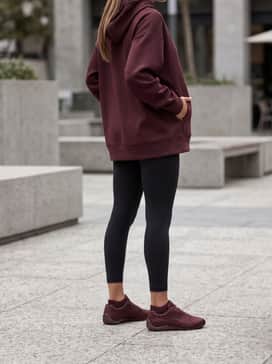 Style with black high-performance leggings, a matching burgundy oversized hoodie, and a sleek ponytail for a coordinated monochromatic athleisure vibe.