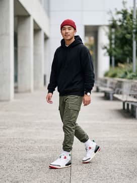 Spizike Low Se – Tapered olive green cargo pants paired with a black oversized graphic hoodie and a red beanie to highlight the shoe's accents.