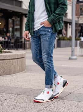 Spizike Low Se – Slim-fit medium-wash distressed jeans, a crisp white heavyweight t-shirt, and an unbuttoned forest green flannel shirt.