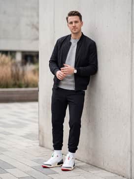 Spizike Low Se – Black nylon joggers with a grey heather crewneck sweatshirt and a sleek black bomber jacket for a modern athletic silhouette.
