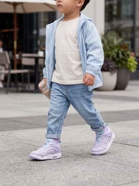 Tapered light-wash denim jeans paired with a crisp white graphic t-shirt and a matching light blue windbreaker for a classic urban look.