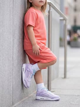 A coral-toned jersey mesh athletic set with white crew socks, providing a vibrant, sporty contrast to the pastel lavender of the sneakers.