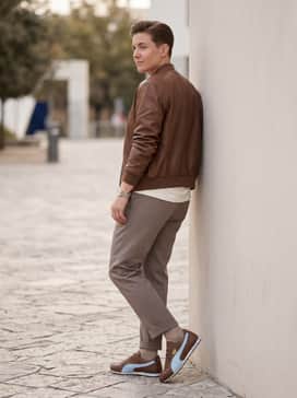 Sprint Sneakers – A midi-length pleated skirt in a neutral taupe, worn with a tucked-in graphic tee and a brown leather bomber jacket for a chic, edgy vibe.