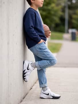 St Dynamite – Classic blue denim jeans with a rolled cuff, a simple navy crewneck sweatshirt, and a bright yellow raincoat for a practical school outfit.