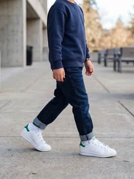 Dark indigo cuffed denim jeans paired with a navy blue crewneck sweatshirt and a bright yellow raincoat for a classic, weather-ready look.