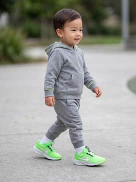 A mini heather-grey hoodie and matching jogger set with subtle neon details that echo the vibrant Volt green of the shoes.