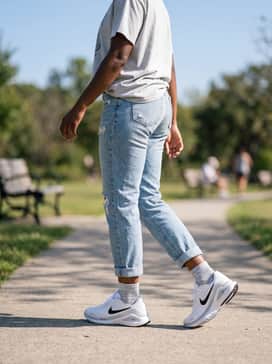 Light-wash distressed girlfriend jeans rolled at the cuff with a tucked-in oversized graphic t-shirt and a classic baseball cap for a sporty-casual weekend outing.