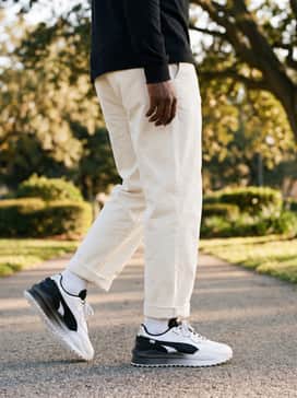 Relaxed-fit cream chinos with a tucked-in black long-sleeve t-shirt and a utility vest for a high-fashion streetwear vibe.