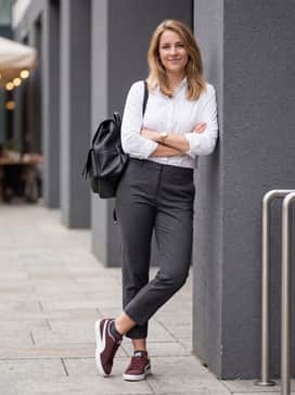 Charcoal grey cropped tailored trousers, a crisp white button-down shirt, and a structured black leather backpack for a smart-casual office ensemble.
