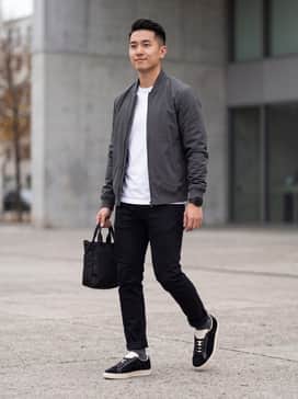Slim-fit black denim jeans paired with a crisp white t-shirt and a charcoal grey bomber jacket for a sleek, monochromatic urban look.