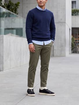 Suede Icons Mens Sneakers – Tapered olive green chinos with a light blue oxford button-down shirt and a navy blue crewneck sweater for a polished weekend ensemble.
