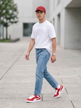 Baggy light-wash denim jeans paired with an oversized white graphic t-shirt and a red baseball cap for a classic streetwear vibe.
