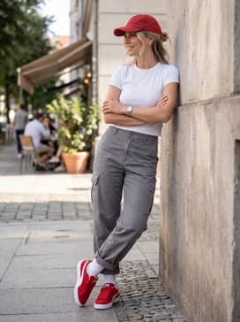 Grey baggy cargo pants combined with a fitted white baby tee and a red baseball cap for a cohesive urban aesthetic.