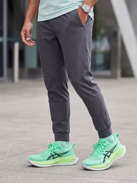 Superblast 2 Ekiden – An urban techwear ensemble with charcoal grey tapered cargo joggers, a fitted black compression long-sleeve shirt, and a reflective silver windbreaker.