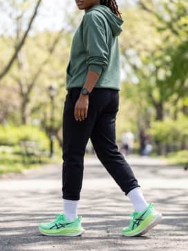 Superblast 2 Ekiden – A casual post-workout style with black tech-fleece joggers, an oversized hoodie in a muted forest green, and white crew socks pulled over the pants hems.
