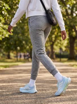 Grey marl tapered joggers combined with a cropped white zip-up hoodie and a sleek crossbody bag for a coordinated post-workout look.