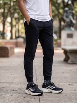Slim-fit black joggers with ribbed cuffs, a crisp white oversized graphic hoodie, and a structured black baseball cap for a modern streetwear-inspired athleisure look.
