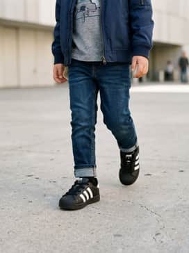 Dark-wash cuffed denim jeans paired with a grey graphic t-shirt and a lightweight bomber jacket for a cool urban look.