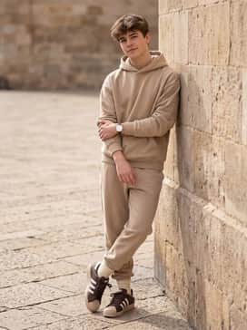 Go for a monochromatic athleisure vibe with sand-colored tapered joggers, a matching oversized hoodie, and visible cream-colored ribbed socks.