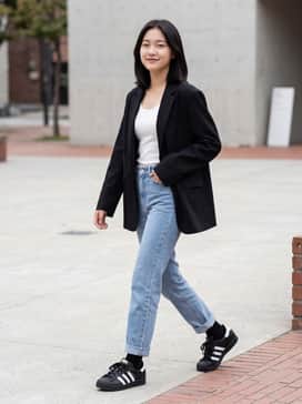 High-waisted straight-leg light-wash jeans paired with a tucked-in white ribbed tank top and an oversized black blazer for a polished yet casual look.
