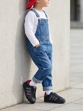 Create a casual weekend outfit by matching the shoes with denim overalls over a simple white long-sleeve tee, finishing the look with a red baseball cap.