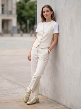 Style with cream-colored tailored linen trousers and a matching waistcoat for a monochromatic, high-end resort aesthetic that highlights the gold tones.