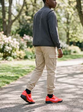 Beige cargo pants tucked into the shoes with a utility vest over a long-sleeve tee for a rugged, outdoor adventure aesthetic.