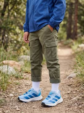 An outdoor-ready ensemble with durable olive green cargo joggers, a royal blue lightweight windbreaker, and a matching baseball cap for sun protection.