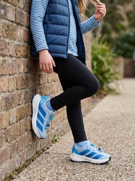 A comfortable school day outfit pairing black fleece-lined leggings with a long-sleeved blue-and-white striped shirt and a lightweight puffer vest.