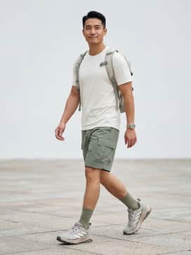 A technical hiking look featuring sage green ripstop cargo shorts, a cream-colored moisture-wicking athletic tee, and earth-toned crew socks pulled high.