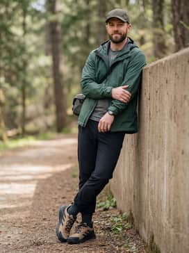Technical black joggers combined with a forest green waterproof rain jacket and a matching moisture-wicking baseball cap for wet-weather utility.