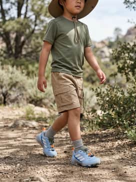 A rugged outdoor look featuring khaki cargo shorts, a moisture-wicking olive green t-shirt, and a protective wide-brimmed sun hat for trail adventures.