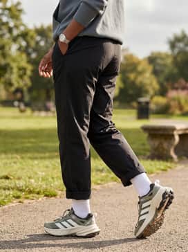 Terrex Freehiker Sl Goretex Hiking Shoes – Water-resistant black nylon track pants tucked into white crew socks, matched with a slate grey oversized hoodie for a practical rainy-day outfit.