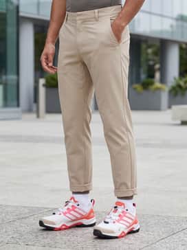 An urban gorpcore look with wide-leg beige utility trousers, a black graphic t-shirt, and a technical multi-pocket vest in white to match the shoe's primary color.